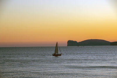 Silhouette sailboat in sea against orange sky