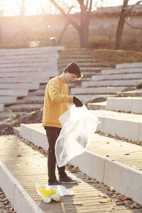 Male volunteer with plastic waste standing on staircase