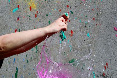 Cropped image of hand bursting water balloon
