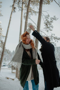 Smiling couple dancing while standing during winter in forest