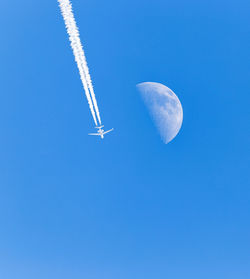 Low angle view of airplane against clear blue sky