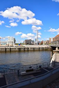 Bridge over river by buildings against sky in city