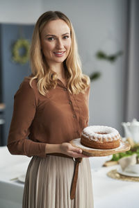 Portrait of smiling woman with cake at home