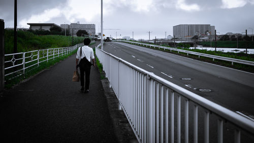 Rear view of man walking on sidewalk in city