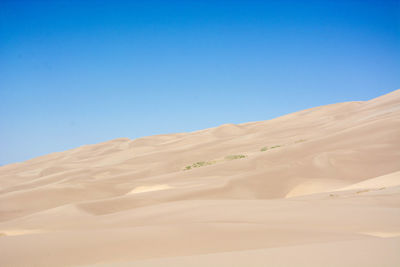 Scenic view of desert against clear blue sky
