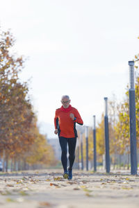 Senior man running on road during autumn