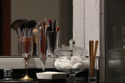 Close-up of beauty products by mirror on table