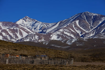 Scenic view of snowcapped mountains against clear blue sky