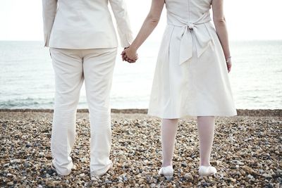 Low section of friends standing on beach