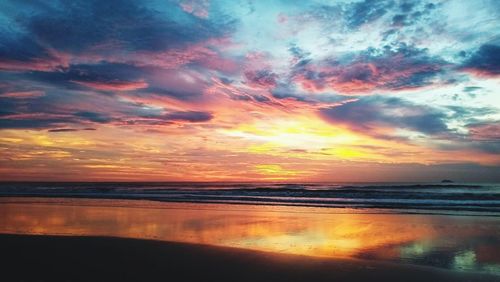 Scenic view of sea against dramatic sky during sunset