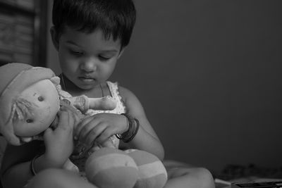 Black and white portrait of a cute baby girl playing with a soft toy