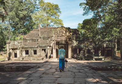 Rear view of woman walking against old temple
