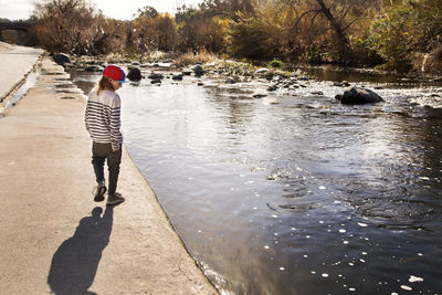 Rear view of boy walking at riverbank