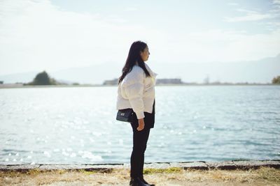 Woman standing by sea against sky
