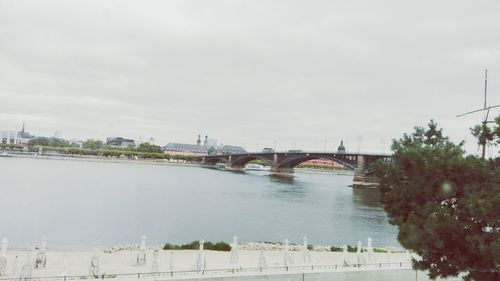 Bridge over river in city against sky