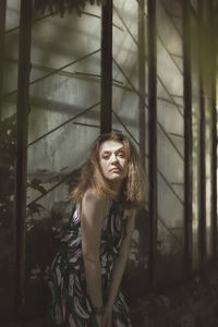 Portrait of young woman standing against wall