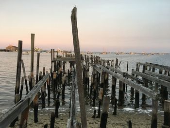 Wooden posts in sea against sky