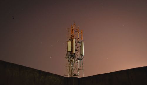 Low angle view of communications tower against sky at night