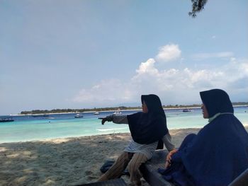 Rear view of people sitting on beach