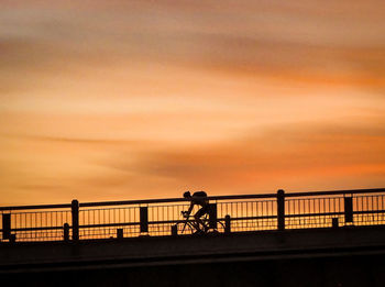 Silhouette people walking on bridge against sky during sunset