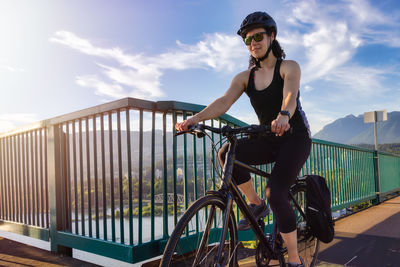 Man riding bicycle on railing against sky