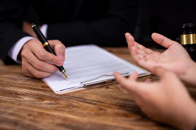 Cropped image of man holding paper on table