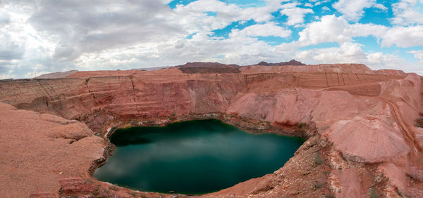 View of rock formations and lake against cloudy sky