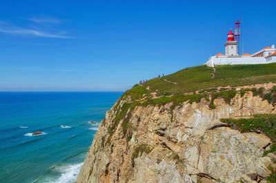 Lighthouse by sea against sky