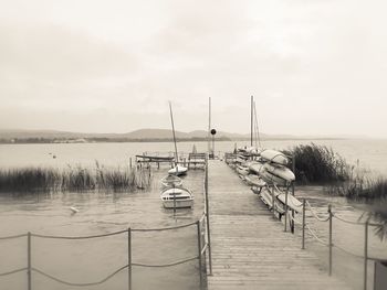 Boats moored by jetty in sea against sky