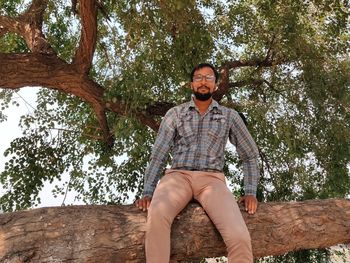 Low angle view of man sitting against trees