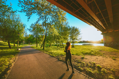 Rear view of woman walking on footpath amidst plants