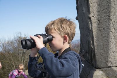Close-up of boy looking through binoculars while standing outdoors