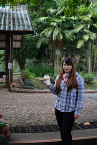 Portrait of smiling young woman standing at park