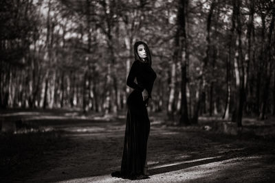 Portrait of woman standing by trees in forest