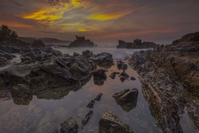 Scenic view of sea against cloudy sky during sunset