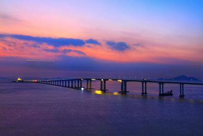 Bridge over sea against romantic sky at sunset