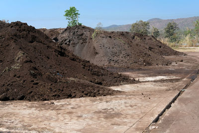 Dirt road leading towards mountains against clear sky