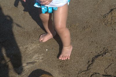 Low section of girl standing on sand at beach