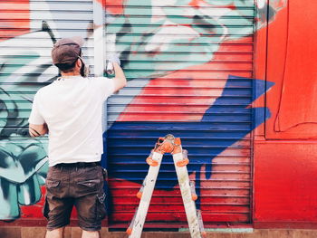 Rear view of man working on wall