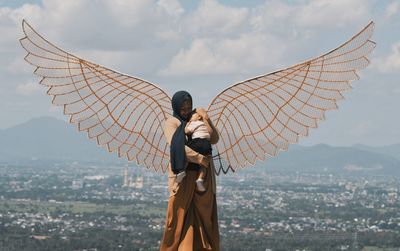 Low angle view of woman standing by cityscape against sky