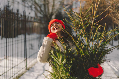 A beautiful girl in a red hat carries a christmas tree. christmas tree