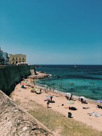 People on beach against clear blue sky