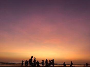 Silhouette people enjoying at beach against sky during sunset