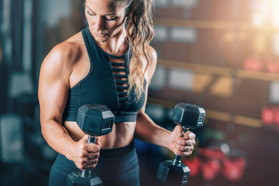 Female athlete doing biceps exercise with dumbbells. strength training.