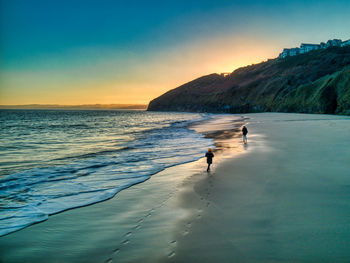 Man on beach against sky during sunset