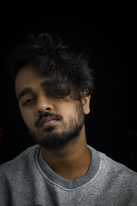 Close-up portrait of young man against black background