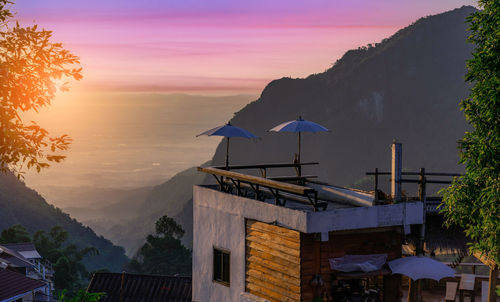 Scenic view of building and mountains against sky during sunset