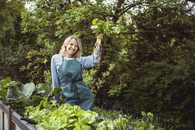 Woman standing by plants against trees