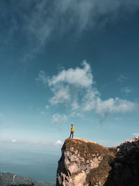 Man standing on rock against sky