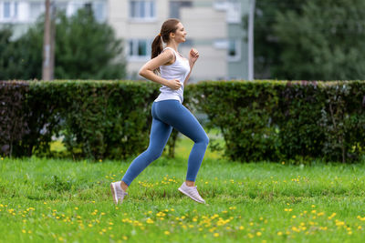 Full length of woman with arms raised on field